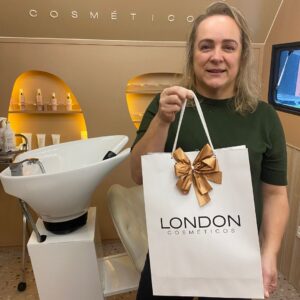 Mulher segurando sacola da London Cosméticos, simbolizando a compra de produtos de beleza e cuidados pessoais.